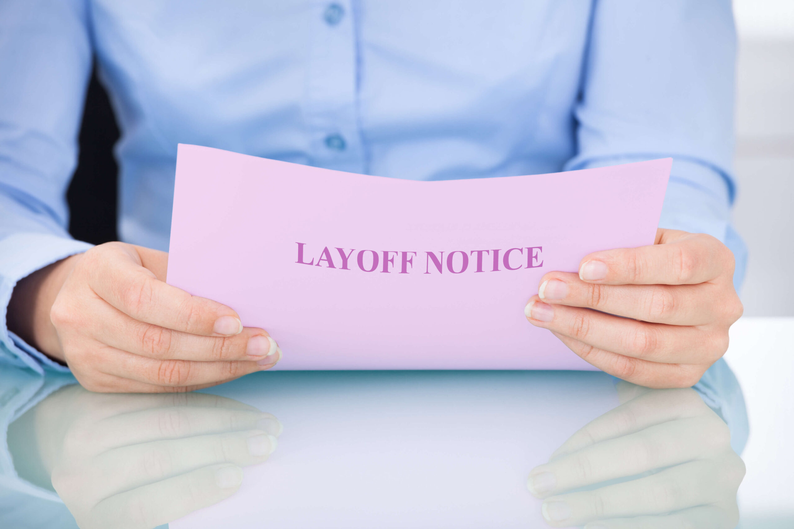 Temporary lay off - man in blue shirt holding a pink piece of paper saying layoff notice
